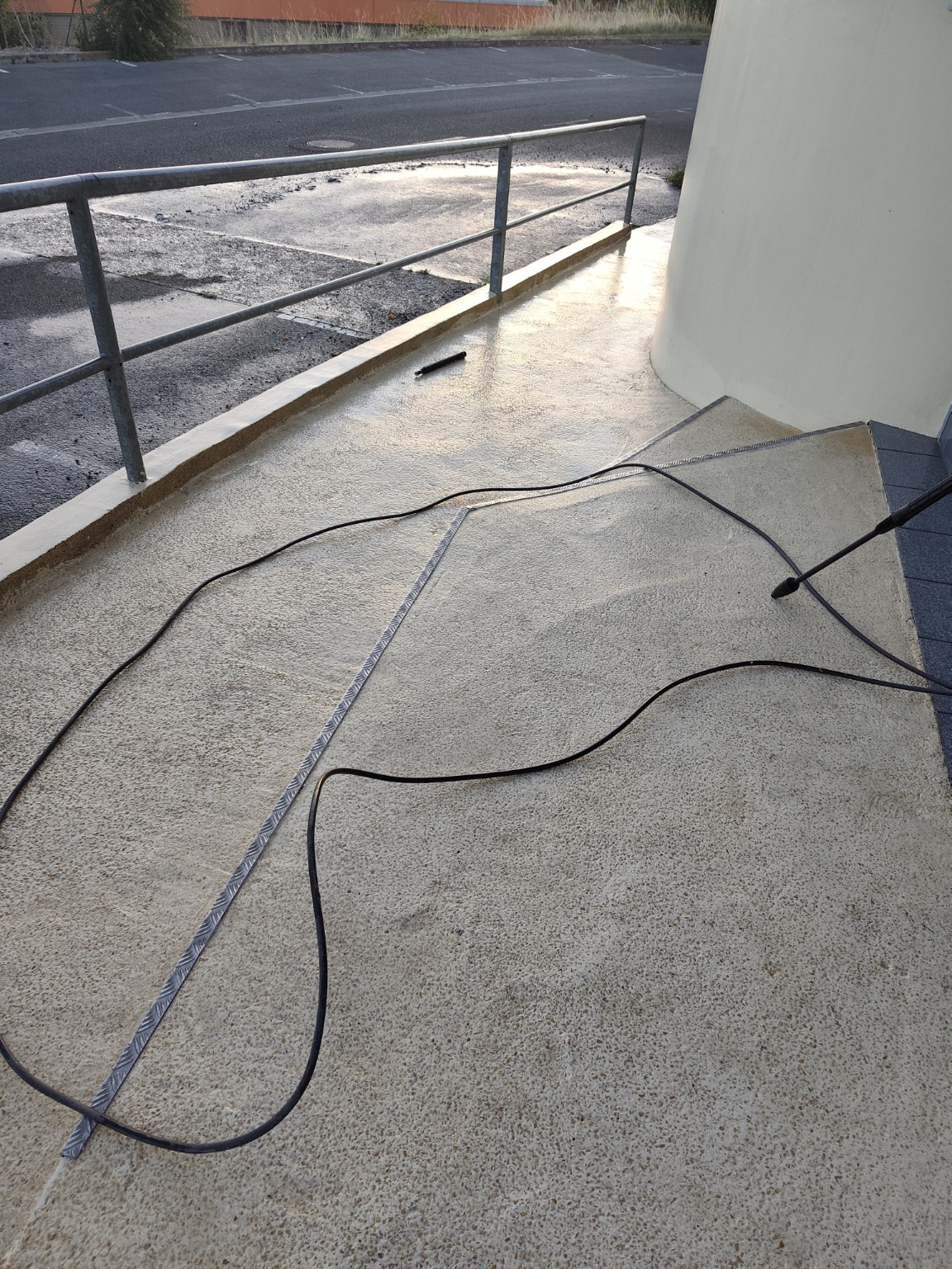 Sol extérieur nettoyé à haute pression, avec le tuyau et la lance encore visibles